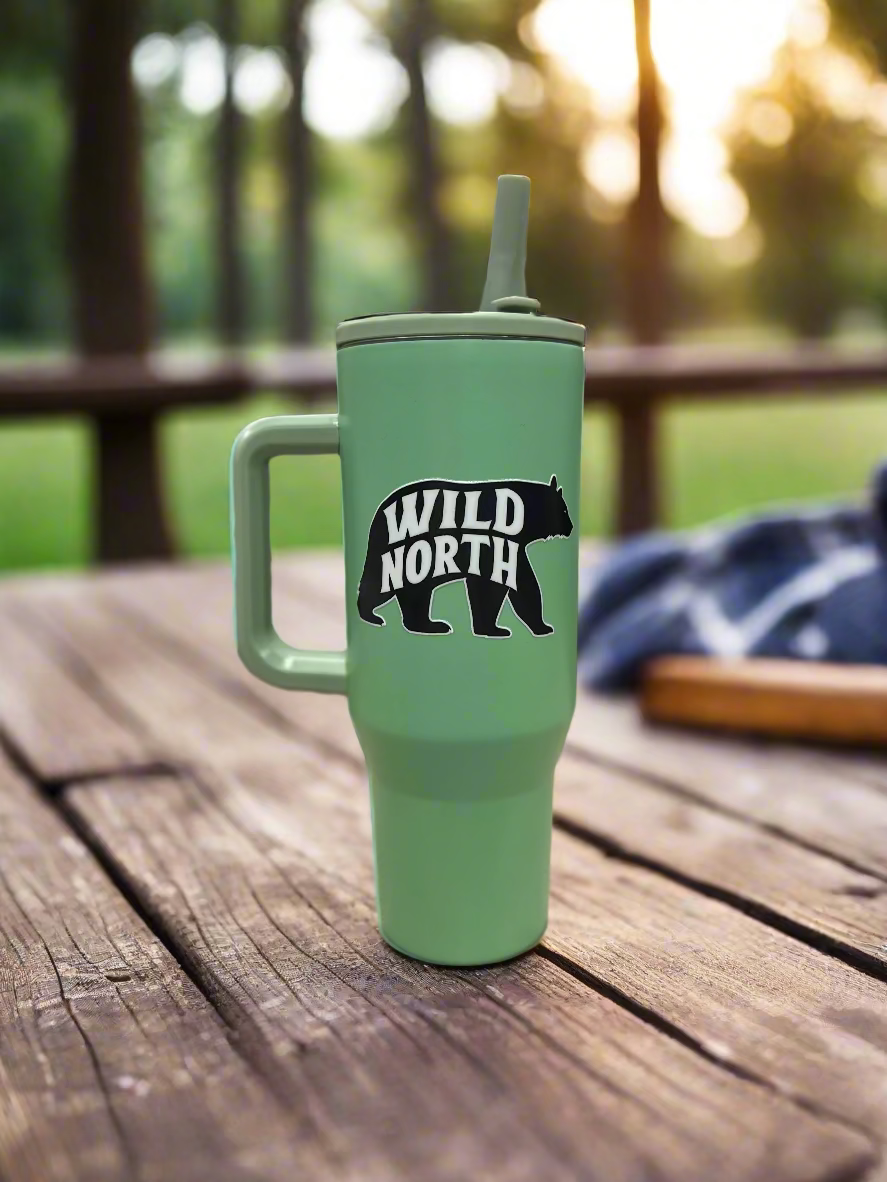 Green tumbler with 'Wild North' bear graphic on a wooden surface