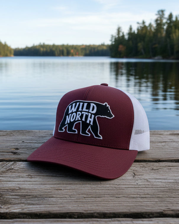 Maroon and white cap with a logo on a wooden surface