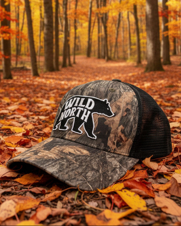 Camouflage cap with a logo on a wooden surface, with a store interior in the background.